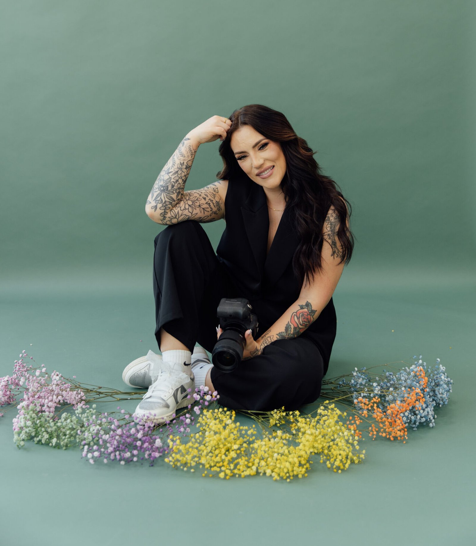 Sarah owner sitting on floor with flowers and camera
